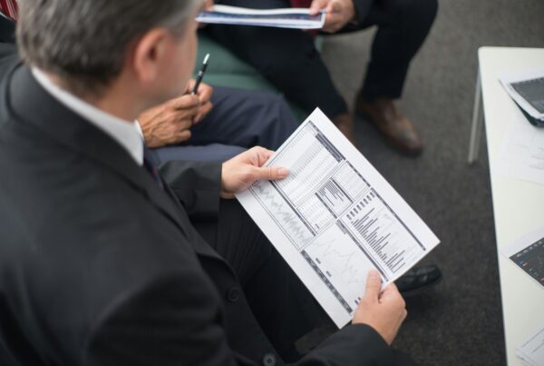 Business leaders reviewing financial charts and reports during a strategy meeting, illustrating HR support during economic uncertainty.
